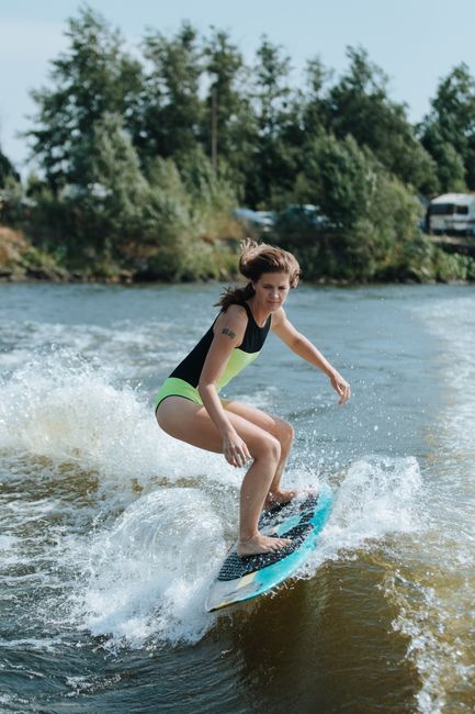 A woman enjoys wakesurfing on a sunny day, showcasing her skills on the water.