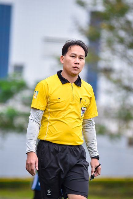Football referee in yellow uniform focuses on the game, capturing the spirit of sportsmanship outdoors.