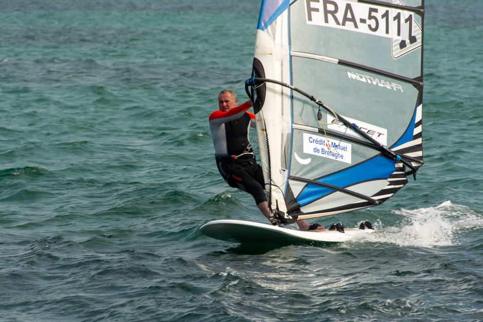 Dynamic windsurfer gliding across the sea, showcasing skill and thrill of water sports.