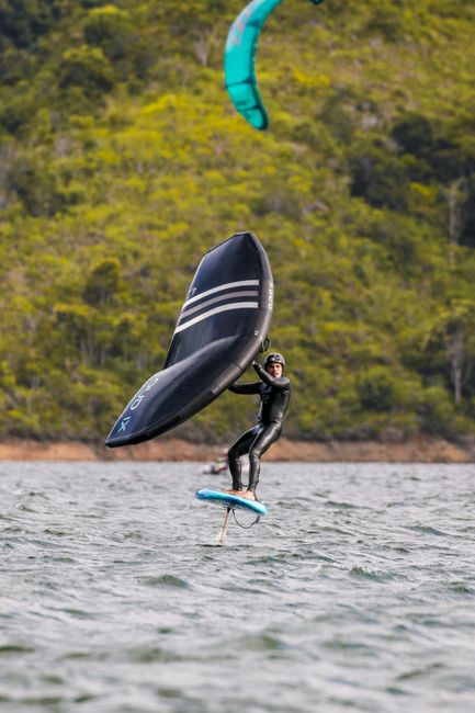 A thrill-seeker enjoying a wing foiling experience in scenic open waters.
