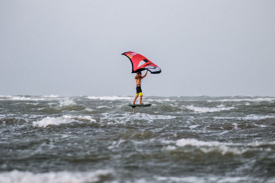 Dynamic scene of a person wing foiling over ocean waves, capturing the thrill of watersport adventure.