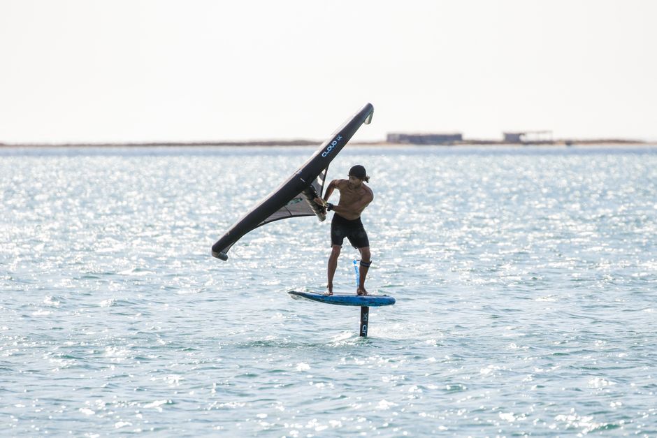 Man wing foiling on a sunny day, showcasing thrilling sea sport action.