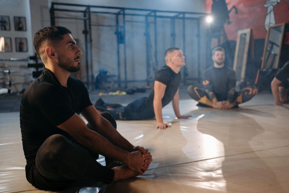 Men engage in stretching exercises inside a gym, focusing on flexibility and fitness.
