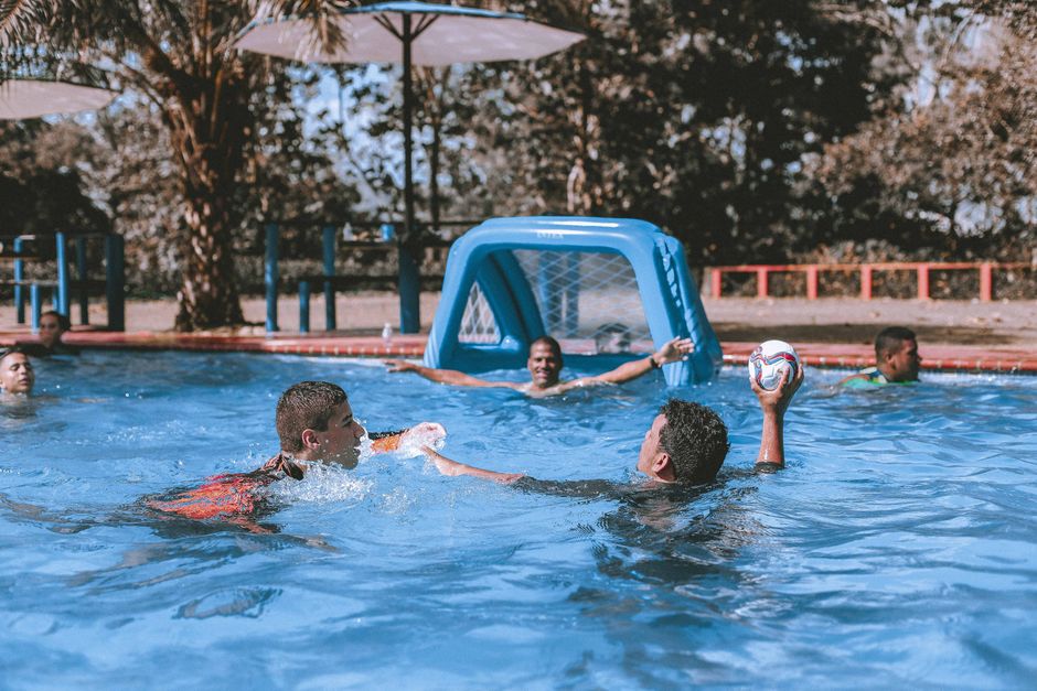 Young adults enjoying a fun and active game of water polo in an outdoor swimming pool.